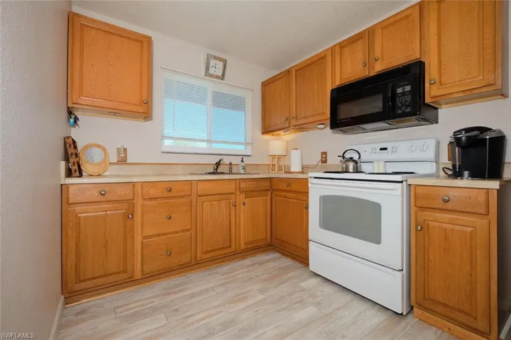 Kitchen with electric range, sink, light hardwood / wood-style floors, and a textured ceiling