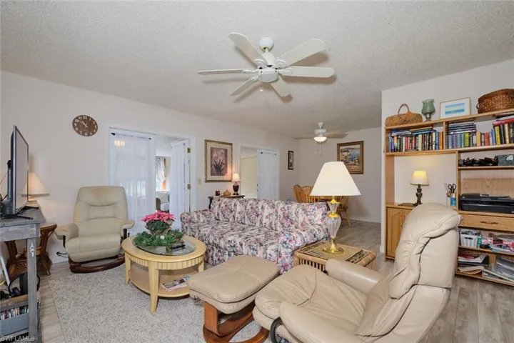 Living room with a textured ceiling, light hardwood / wood-style flooring, and ceiling fan