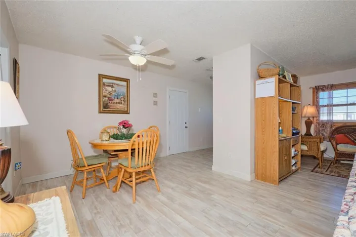 Dining area featuring ceiling fan, light wood-type flooring, and a textured ceiling