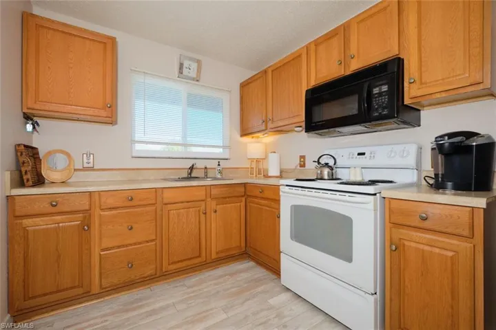 Kitchen featuring white electric range, a textured ceiling, light hardwood / wood-style floors, and sink