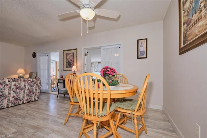 Dining room with ceiling fan, a textured ceiling, and light wood-type flooring