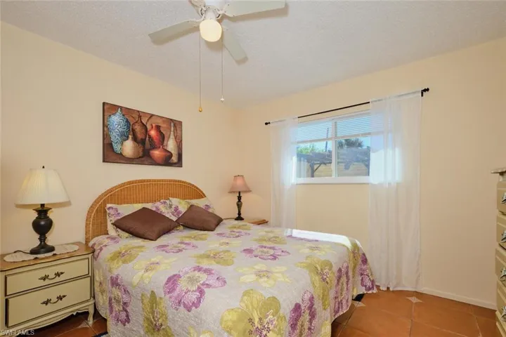 Tiled bedroom featuring ceiling fan and a textured ceiling