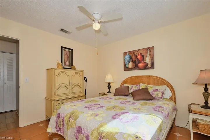 Bedroom featuring ceiling fan, light tile patterned floors, and a textured ceiling