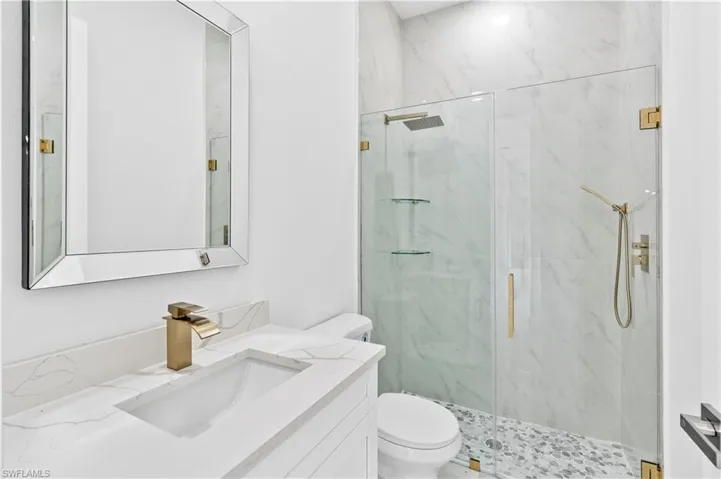 Bathroom featuring vanity, toilet, and a shower with door