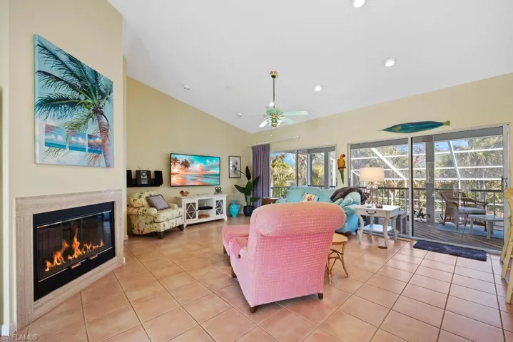 Living room featuring vaulted ceiling, ceiling fan, and light tile patterned flooring