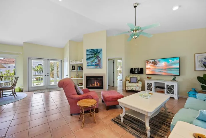 Tiled living room with french doors, high vaulted ceiling, and ceiling fan