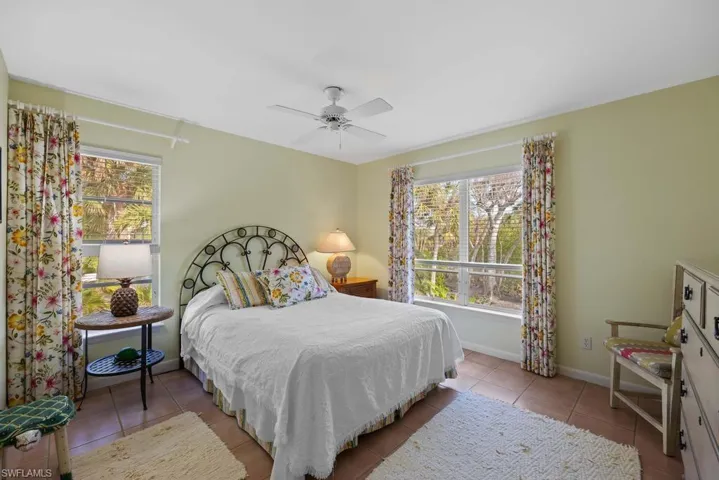 Tiled bedroom with ceiling fan and multiple windows
