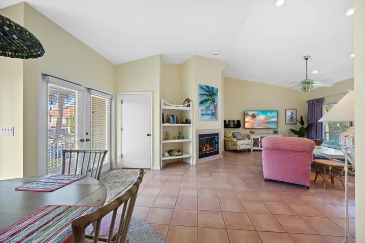 Living room featuring french doors, ceiling fan, built in features, lofted ceiling, and light tile patterned flooring