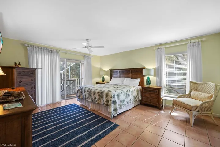 Tiled bedroom featuring multiple windows, access to outside, and ceiling fan