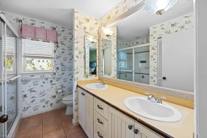 Bathroom with walk in shower, tile patterned flooring, vanity, and toilet