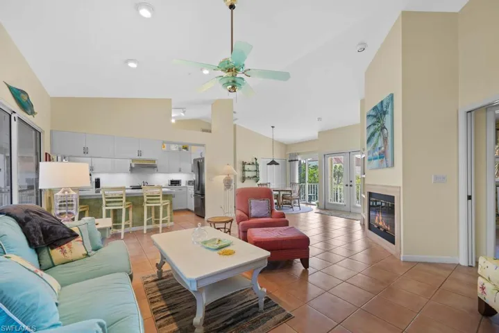 Tiled living room with ceiling fan, french doors, and high vaulted ceiling