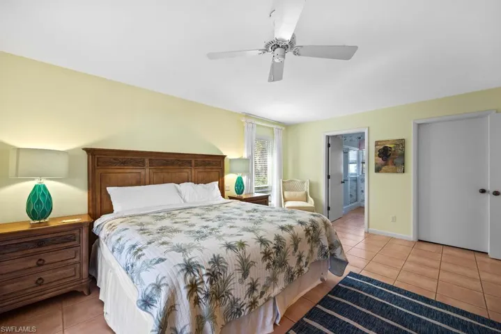 Tiled bedroom featuring connected bathroom and ceiling fan