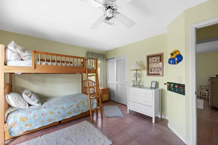 Bedroom with ceiling fan, a closet, and dark tile patterned flooring