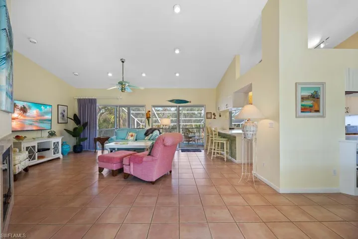 Tiled living room with ceiling fan and high vaulted ceiling