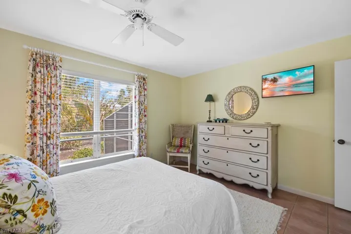 Tiled bedroom featuring ceiling fan