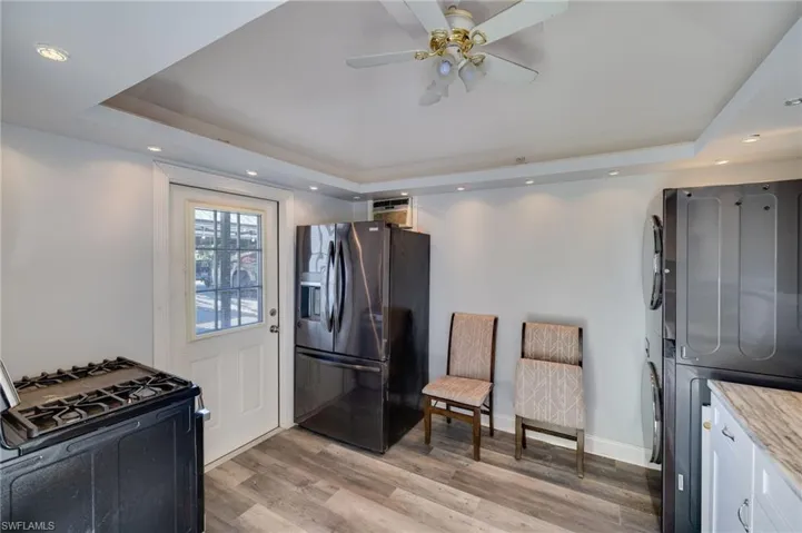 Kitchen featuring black appliances, recessed lighting, light wood-style flooring, a tray ceiling, and white cabinetry