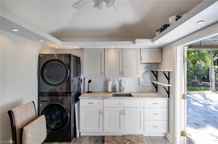 Laundry area featuring recessed lighting, light wood-type flooring, stacked washer / drying machine, cabinet space, and ceiling fan