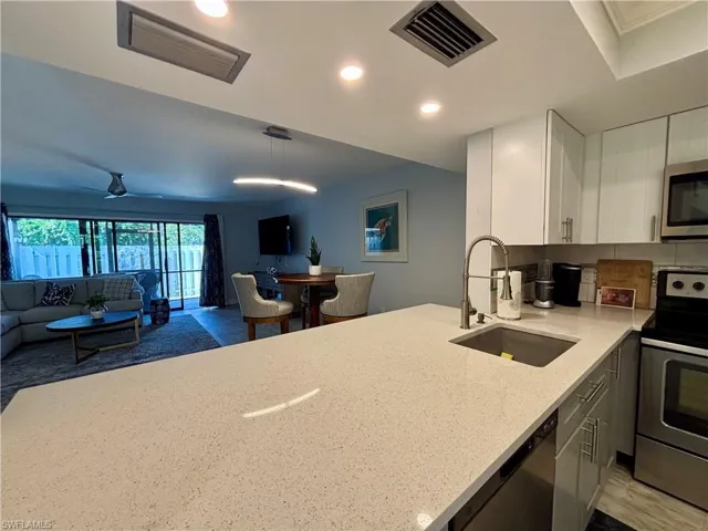 Kitchen featuring appliances with stainless steel finishes, white cabinetry, light stone countertops, recessed lighting, and wood finished floors