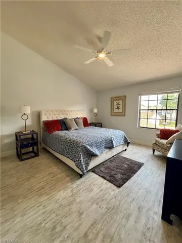 Bedroom featuring wood finished floors, a textured ceiling, ceiling fan, and vaulted ceiling