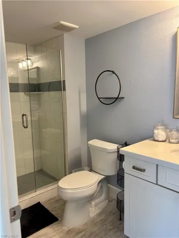 Bathroom with wood finished floors, vanity, a stall shower, and a textured wall