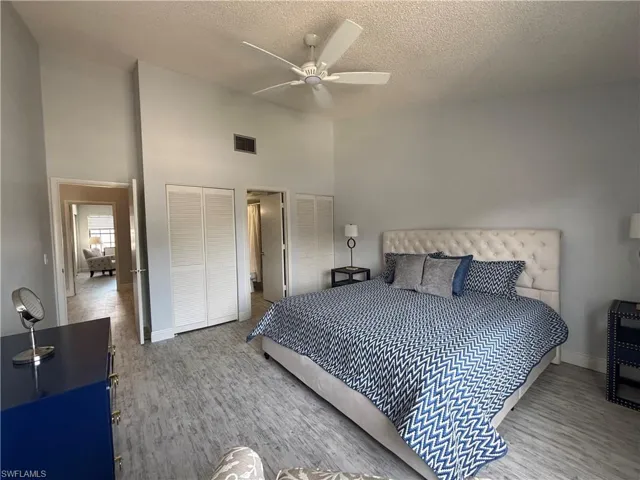 Bedroom featuring wood finished floors, a high ceiling, a textured ceiling, and ceiling fan