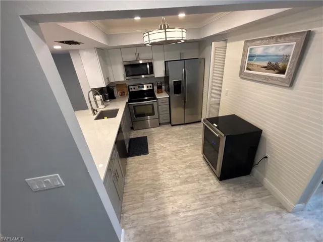 Kitchen featuring appliances with stainless steel finishes, ornamental molding, light countertops, a tray ceiling, and gray cabinets