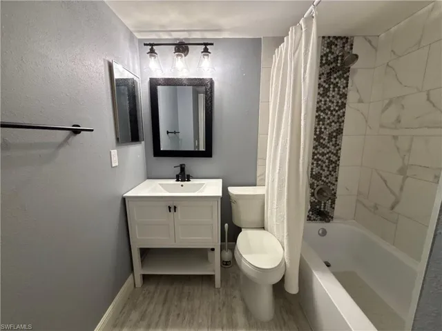 Full bathroom featuring vanity, shower / bath combo with shower curtain, and wood finished floors