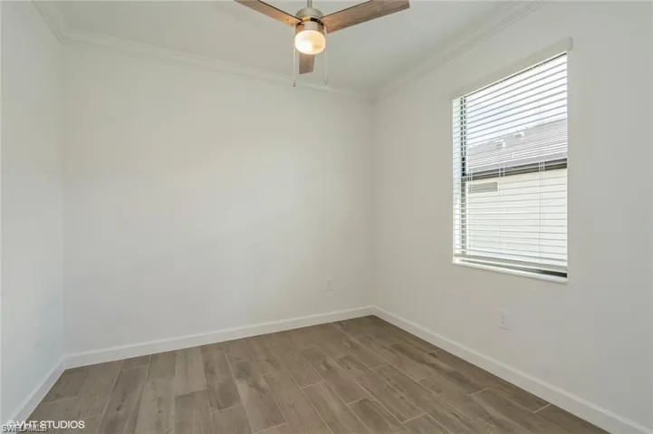 Spare room with ornamental molding, wood finished floors, and ceiling fan