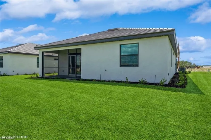 Rear view of property with a lawn, stucco siding, and a sunroom