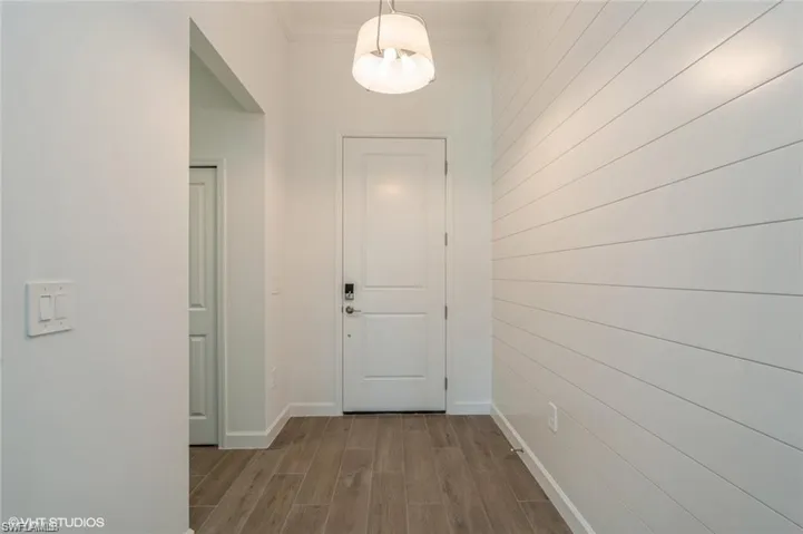 Corridor featuring wood tiled floors, wooden walls, and ornamental molding