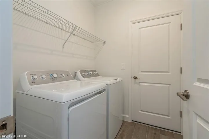 Laundry area featuring wood tiled floors, washer and clothes dryer, and ornamental molding
