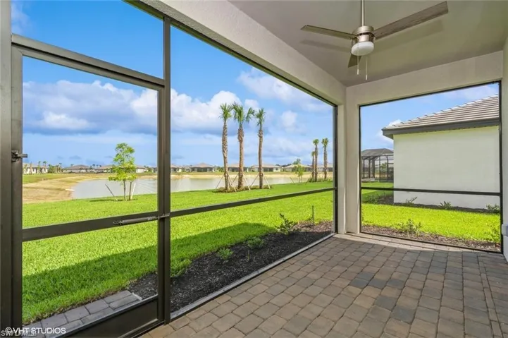 Unfurnished sunroom featuring ceiling fan, a water view, a residential view, and a patio area