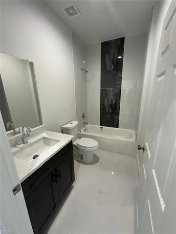 Full bathroom featuring vanity, shower / tub combination, and light marble finish floors