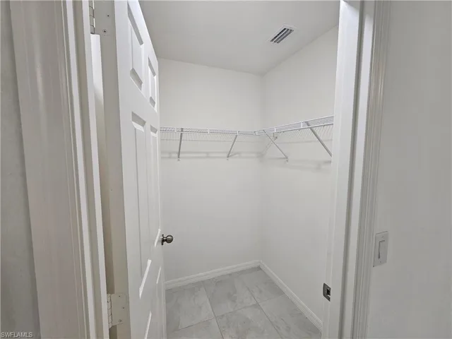 Walk-in closet featuring wire shelving, tile flooring, and a paneled door with a round knob