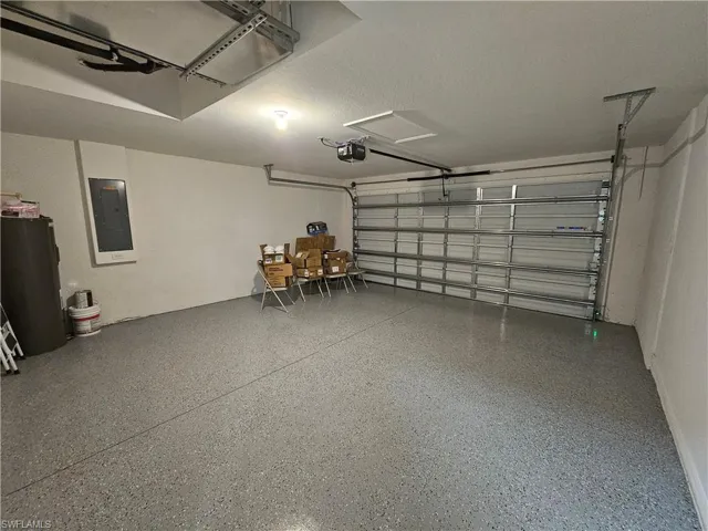 Spacious garage featuring a durable epoxy-coated floor, automatic garage door opener, and overhead track lighting