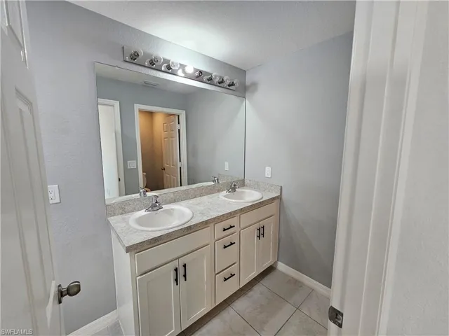 Dual vanity featuring white cabinetry with black hardware, light-toned countertop, and undermount sinks