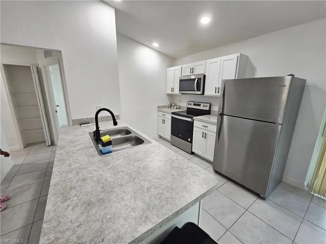 Modern kitchen featuring an island with a double basin stainless steel sink and matte black faucet