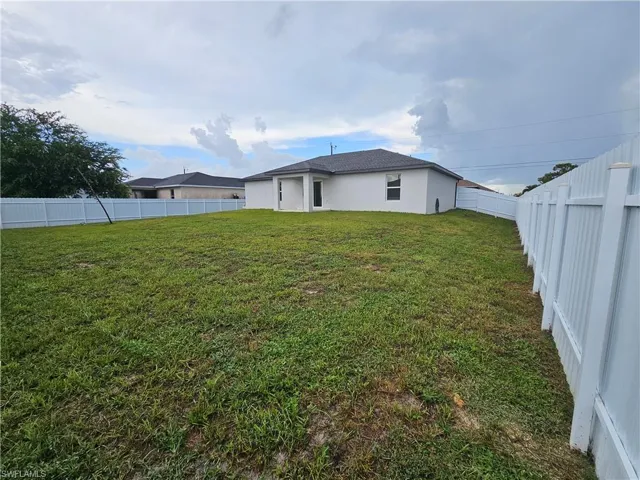 Expansive backyard with a manicured lawn, complete vinyl fencing, and a contemporary rear exterior