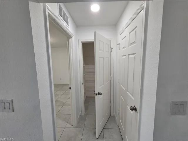 Tiled hallway featuring recessed lighting and multiple panel doors