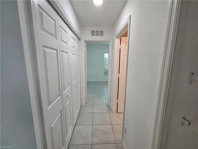 Hallway featuring light tile flooring, white walls, and a white bi-fold closet door