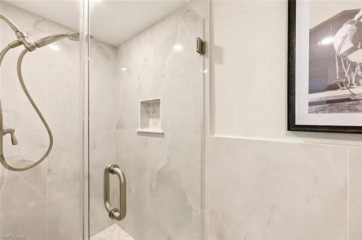 Full bath with a marble finish shower