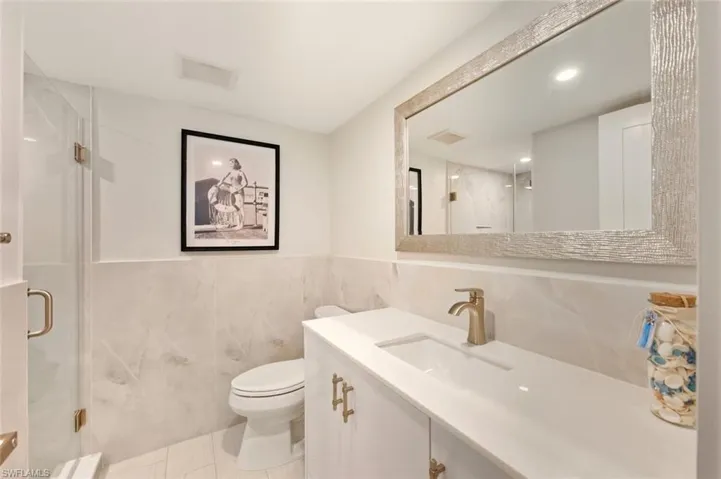 Full bath featuring a shower stall, tile walls, vanity, light tile patterned floors, and recessed lighting
