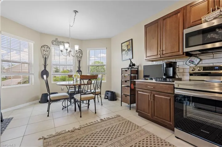Kitchen with stainless steel appliances, a chandelier, baseboards, backsplash, and light tile patterned floors