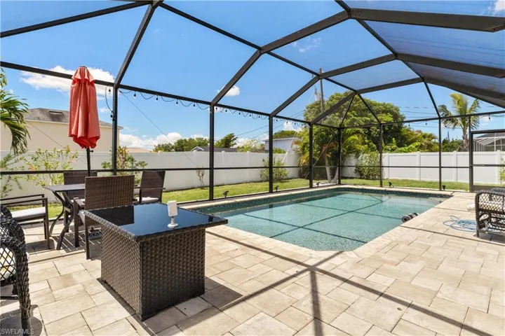 View of pool with a patio area, glass enclosure, a fenced backyard, and outdoor dining space