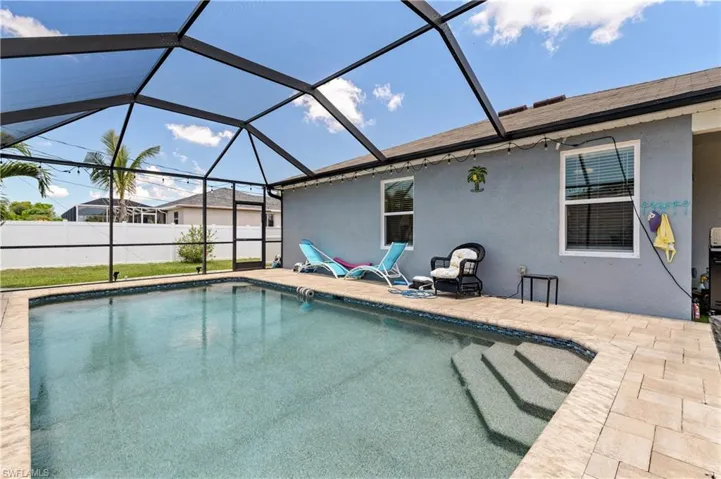 View of swimming pool featuring a patio area, glass enclosure, and fence