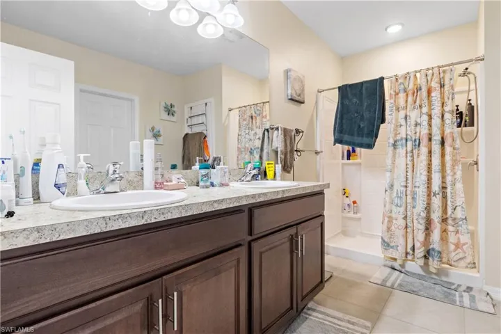 Bathroom with a stall shower, double vanity, and tile patterned floors