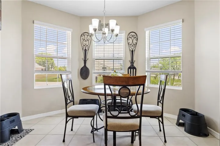 Dining area featuring a chandelier, light tile patterned flooring, and baseboards