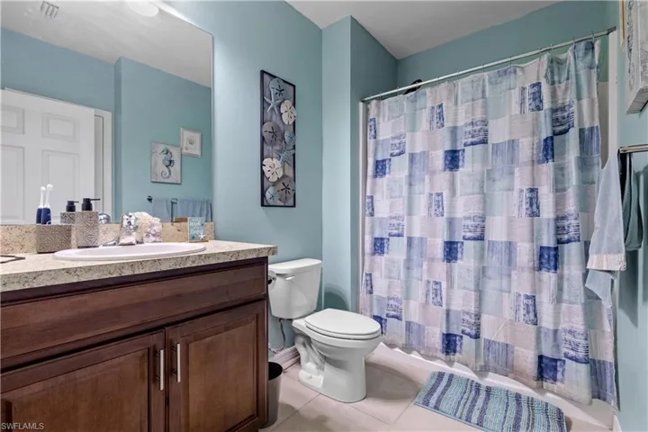 Full bathroom with tile patterned floors, toilet, vanity, and a shower with curtain
