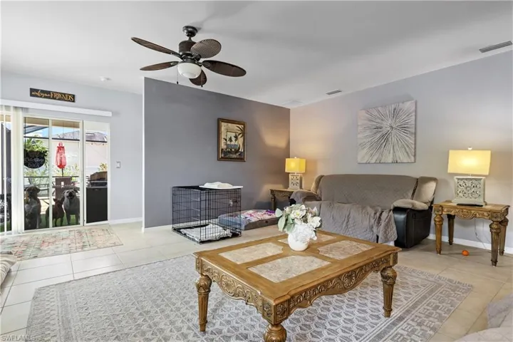 Living room with light tile patterned flooring, ceiling fan, and baseboards