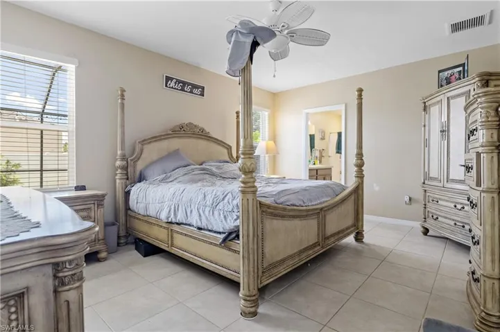 Bedroom with light tile patterned flooring, baseboards, a ceiling fan, and connected bathroom